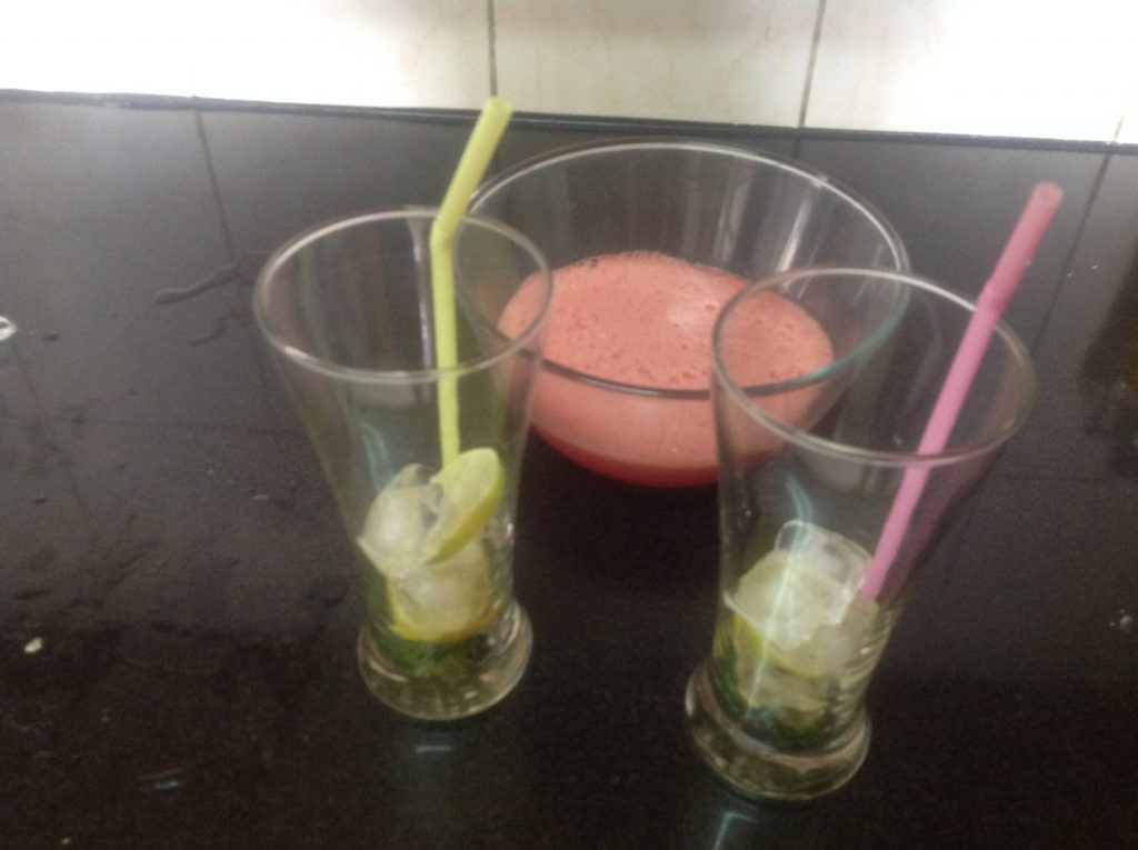 Glass with ice cubes, lemon and crushed mint for watermelon mojito